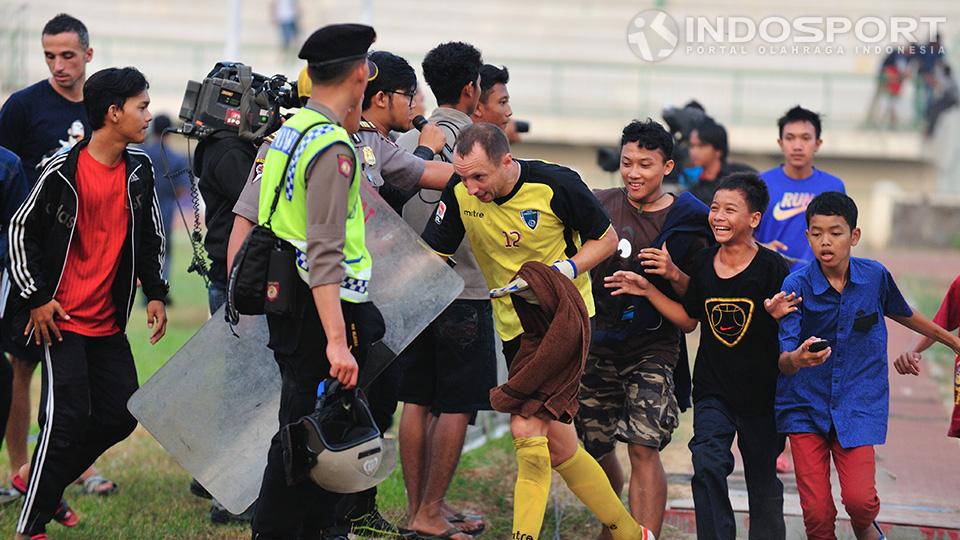 Penjaga gawang PBR Denis Romanov dikejar-kejar oleh pendukung fanatik PBR yang memasuki lapangan setelah memastikan PBR menang atas Persita dan lolos pada babak delapan besar di stadion Singaperbangsa, Karawang, Jumat (05/09/14).
